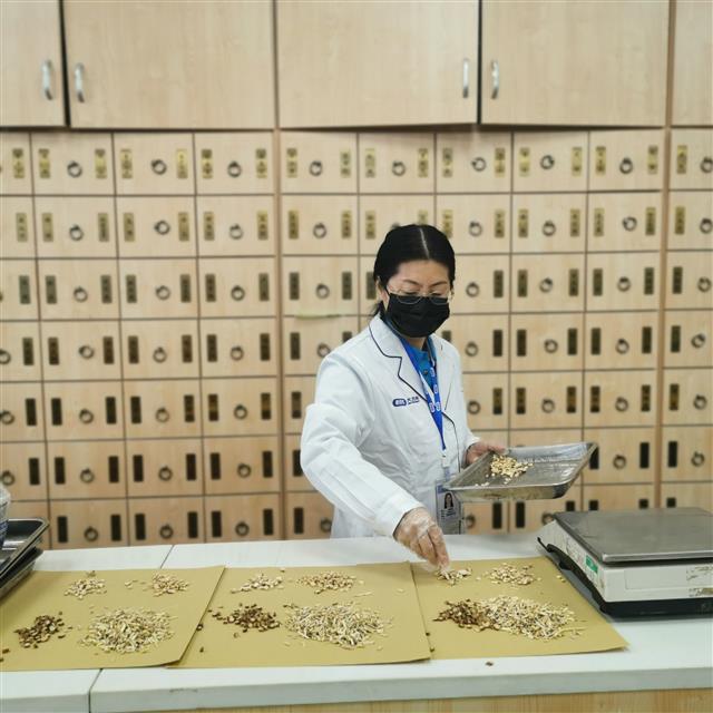 　侯惠鳴為顧客抓藥。